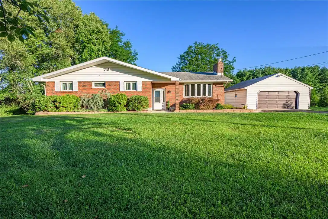 Image 1: A well-maintained brick ranch home with an attache