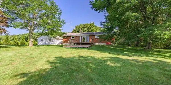 Image 4: A spacious backyard with mature trees, a well-main