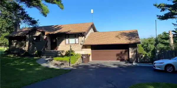 Image 2: Mature trees frame a classic brick ranch home comp