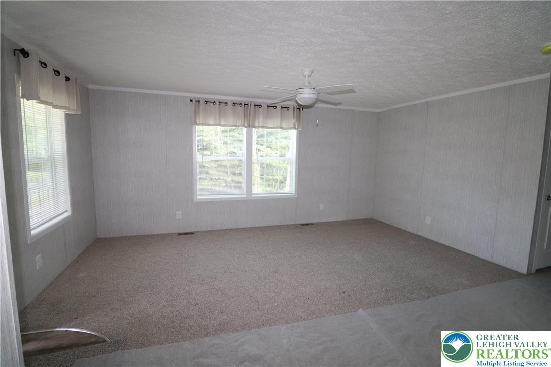 Image 4: Comfortable carpeting and a ceiling fan create a r