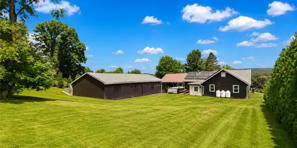 Image 2: An expansive green lawn surrounds the home and det