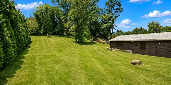 Image 3: Mature trees frame a rolling green lawn next to a