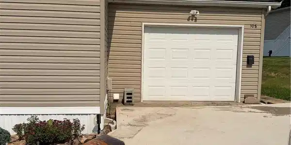 Image 3: A well-maintained garage with neutral siding and a