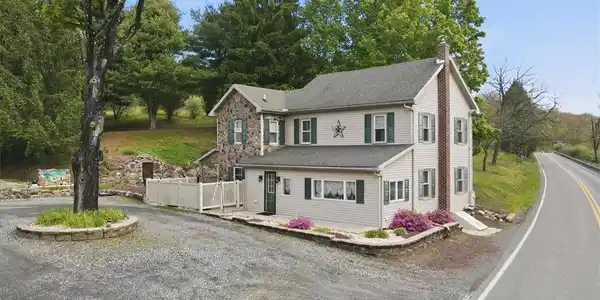 Image 3: This charming home features a timeless stone and s