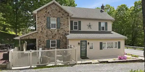 Image 4: This charming home features a captivating stone an