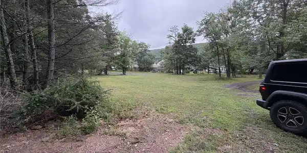 Image 4: A spacious, verdant lot awaits your vision, framed