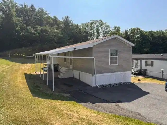 Image 1: A manufactured home with an attached carport sits