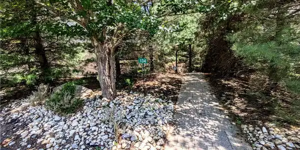 Image 3: A winding paver pathway leads through lush trees a