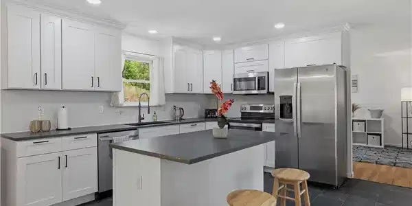 Image 3: White cabinetry, stainless appliances, and a centr