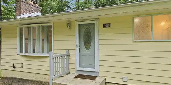 Image 2: Concrete steps lead up to a classic entry framed b