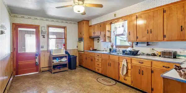 Image 2: Ample wooden cabinetry and vinyl flooring define t