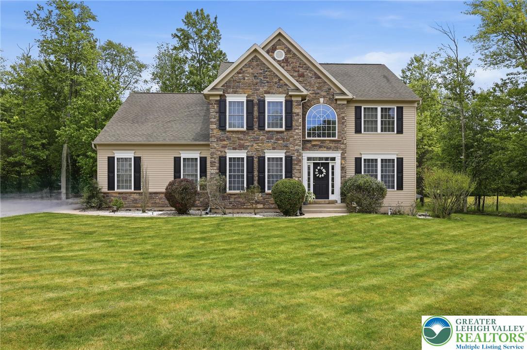 Image 1: A classic facade of stone and siding greets with a