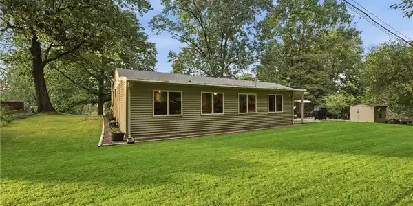 Image 3: Mature trees frame a grassy lawn sloping toward th