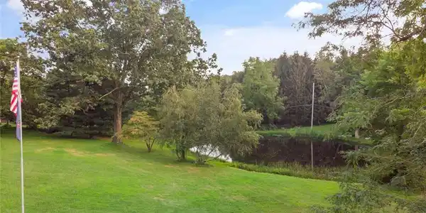 Image 3: Mature trees frame a peaceful private pond on this
