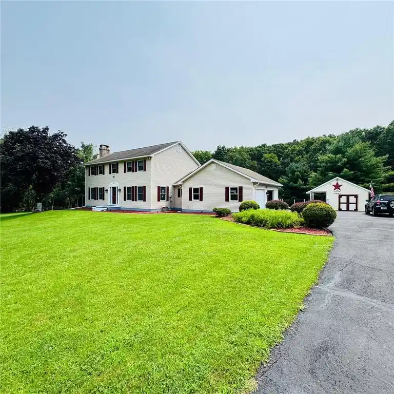 Image 1: A classic colonial home features a verdant lawn, a