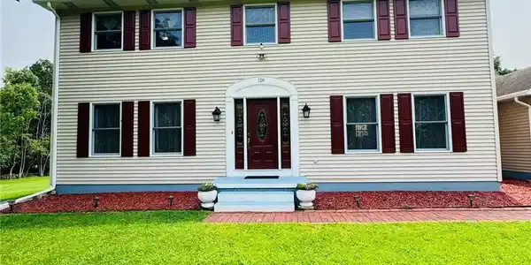 Image 3: A classic two-story facade with warm siding and de