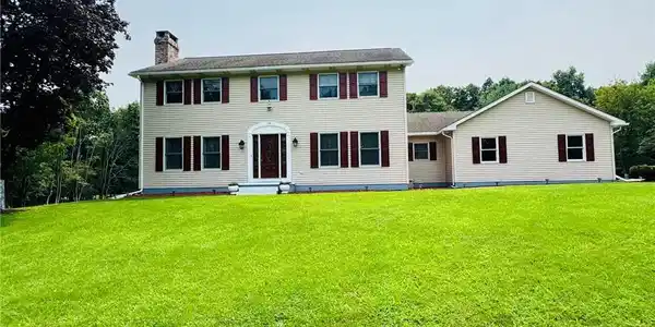 Image 4: A classic two-story home features a vibrant red en