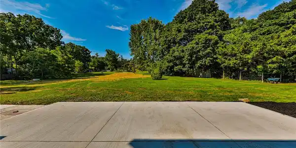 Image 3: A spacious green lawn provides a serene backdrop f