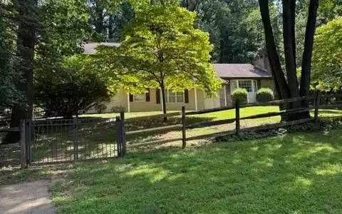 Image 2: A classic home, nestled amongst lush trees, offers