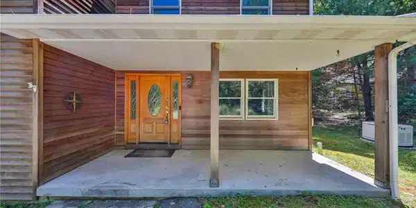 Image 4: A welcoming front porch features a wood entry door