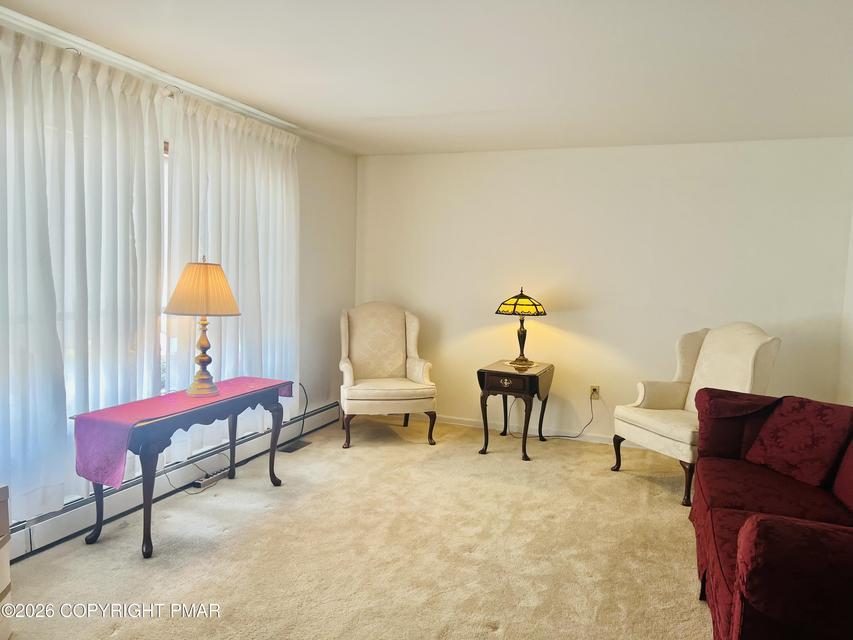 Image 3: A well-lit living area offers plush carpeting and