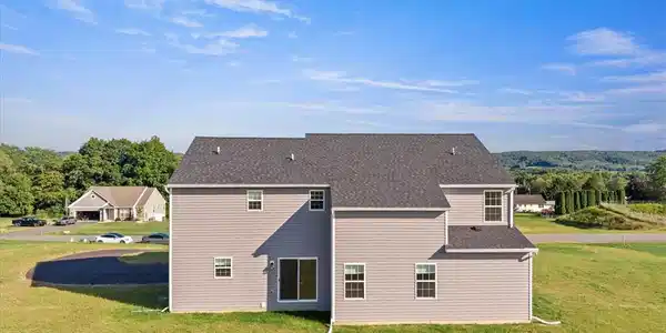 Image 3: A new construction home with gray siding and a vas