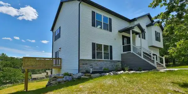 Image 2: Perched on a grassy hill, this charming two-story