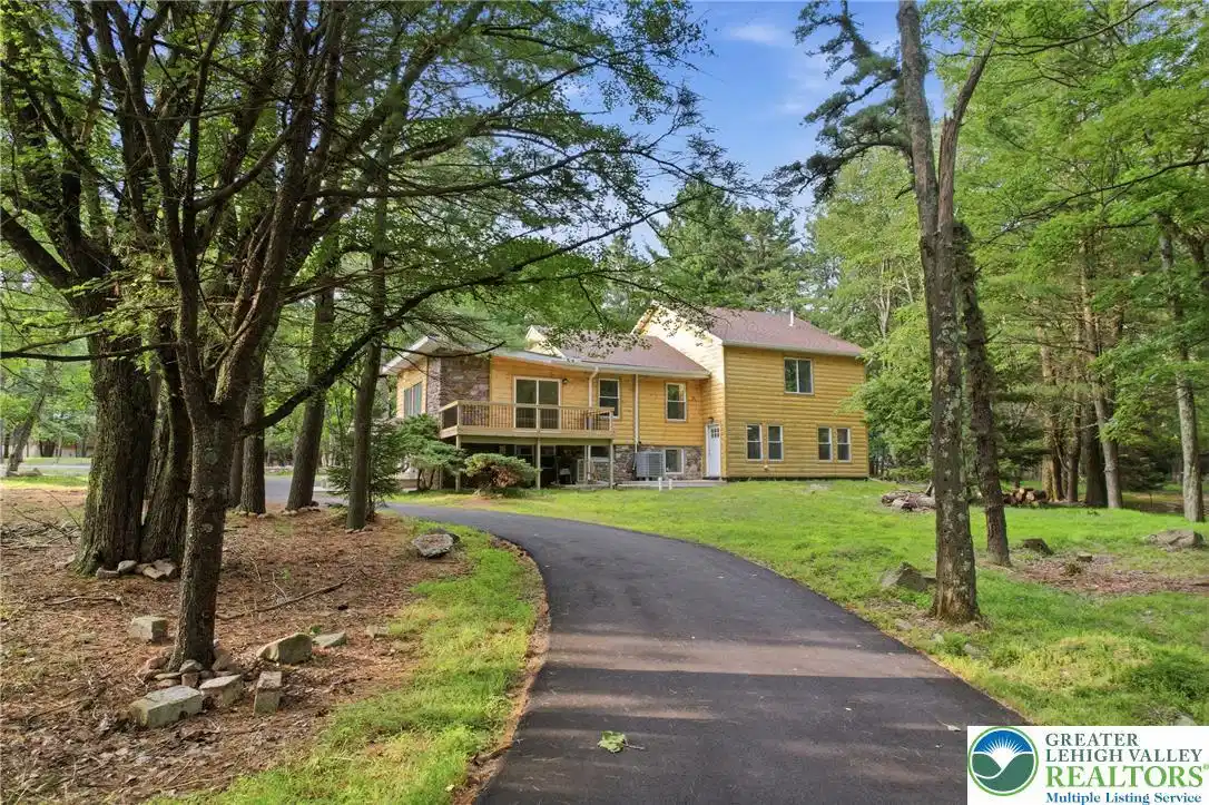 Image 1: A long, curving driveway leads to a welcoming home