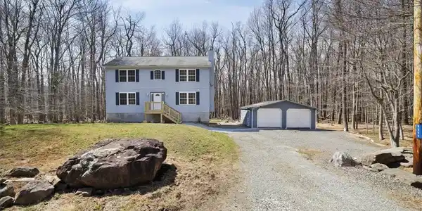 Image 3: Nestled among mature trees, this two-story home fe