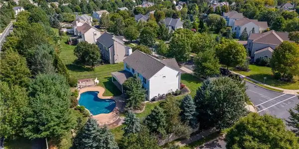 Image 4: Lush mature trees surround a private backyard pool