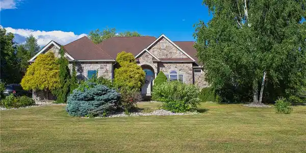 Image 3: A classic stone-faced residence framed by verdant
