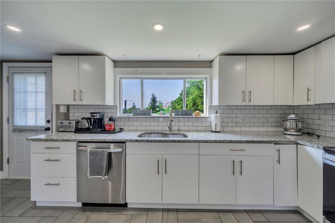 Image 3: A well-appointed kitchen features ample white cabi