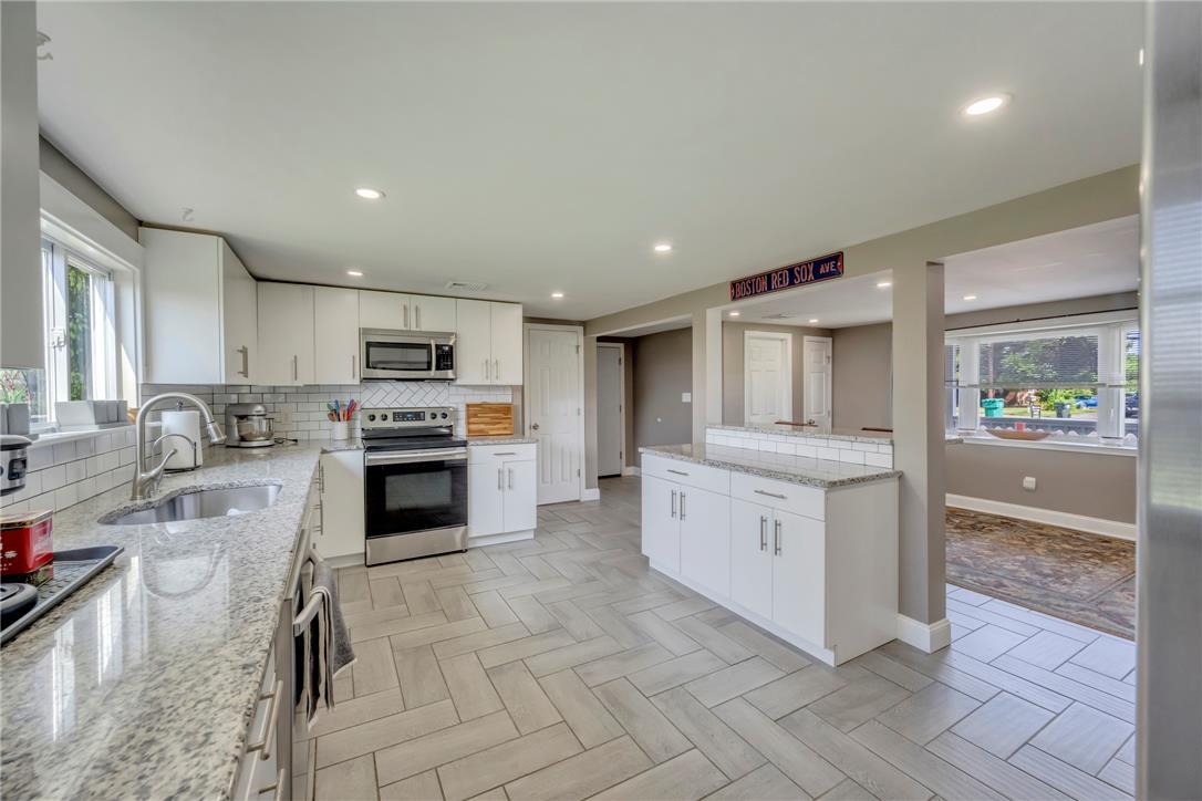 Image 4: A well-appointed kitchen features sleek white cabi