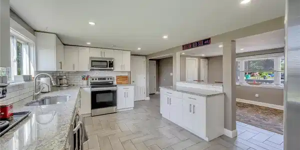 Image 4: A well-appointed kitchen features sleek white cabi