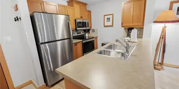 Image 4: Kitchen featuring stainless steel appliances, wood cabinetry, a double basin sink with chrome faucet, and neutral-toned countertops Image 4: Kitchen featuring stainless steel appliances, wood cabinetry, a double basin sink with chrome faucet, and neutral-toned countertops