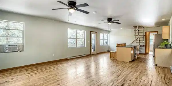 Image 3: Bright, open-concept living with beautiful wood flooring, abundant natural light, and seamless flow into the kitchen.