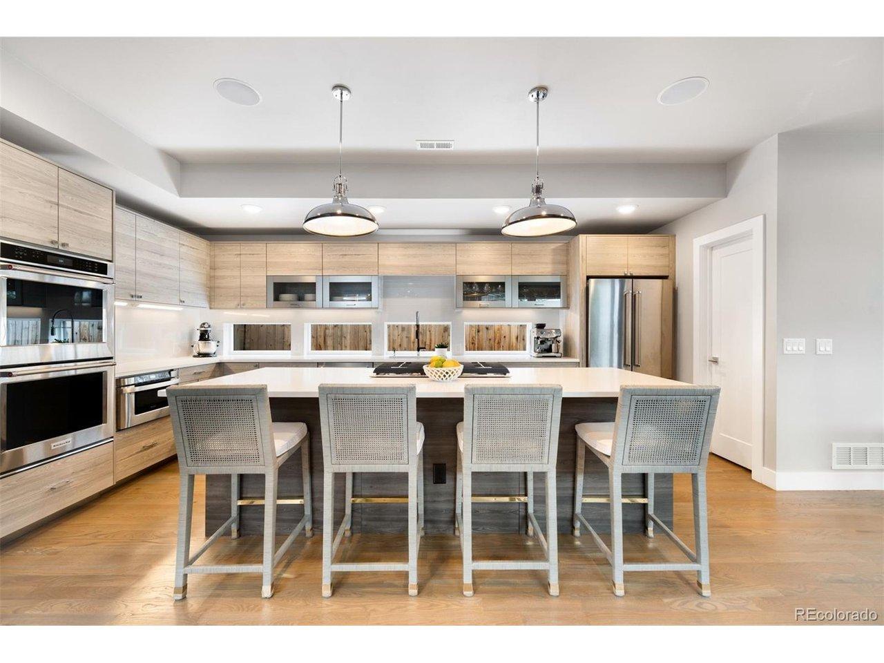 Image 1: The sleek kitchen blends style with practicality, featuring quartz countertops, stainless steel appliances, double ovens, a gas range, overhead lift cabinetry, an eat-in island, and walk-in pantry.