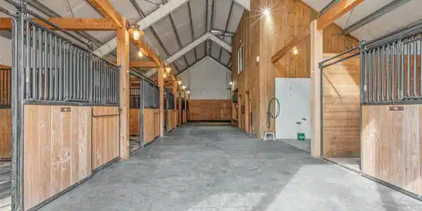 Image 4: Interior custom built in 2009. 6 Horse stalls with mats. Barn opens to corral on North side. Wash stall with hot and cold water. 3 floor drains in alleyway. Image 4: Interior custom built in 2009. 6 Horse stalls with mats. Barn opens to corral on North side. Wash stall with hot and cold water. 3 floor drains in alleyway.
