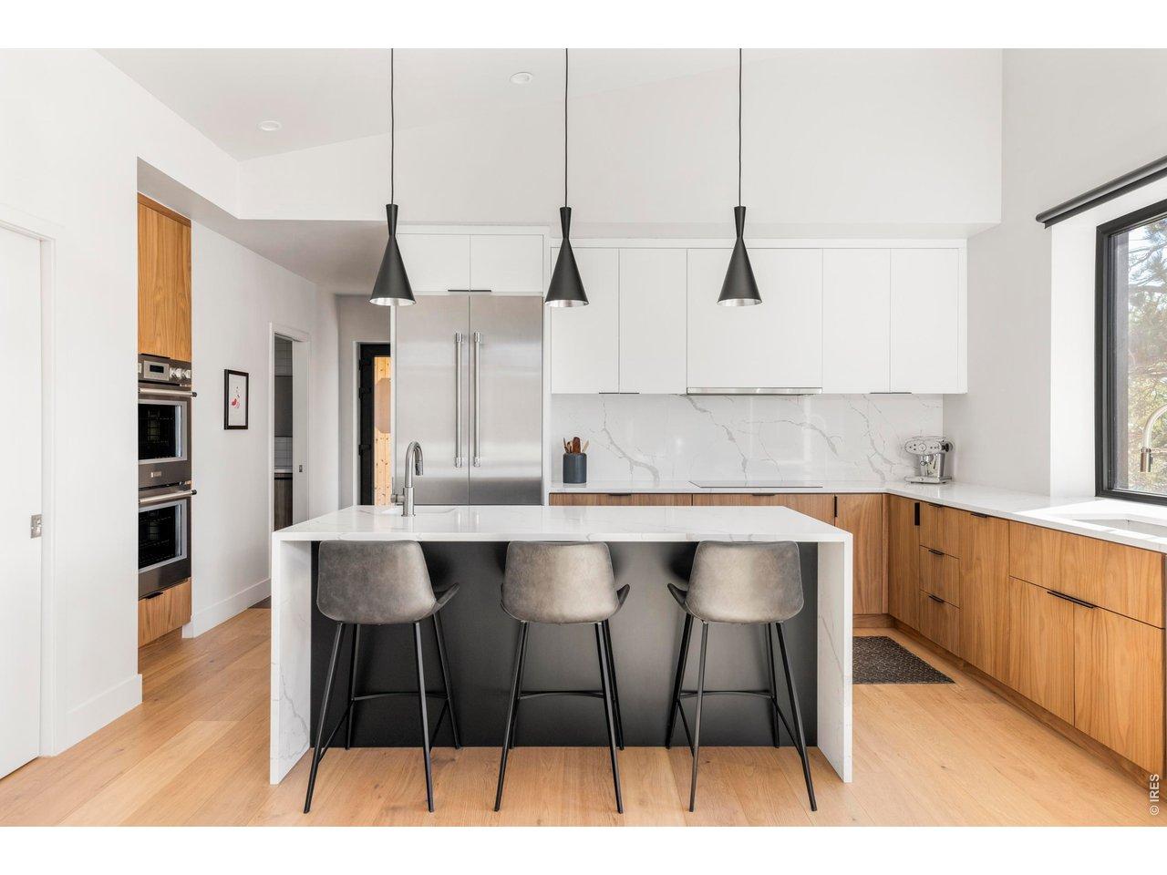 Image 4: Custom wood cabinetry, a quartz waterfall island, and Thermador appliances create a kitchen that feels both refined and highly functional. Image 4: Custom wood cabinetry, a quartz waterfall island, and Thermador appliances create a kitchen that feels both refined and highly functional.
