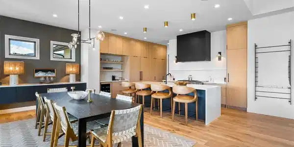 Image 3: Open-concept dining anchored by custom cabinetry and a quartz waterfall island.
