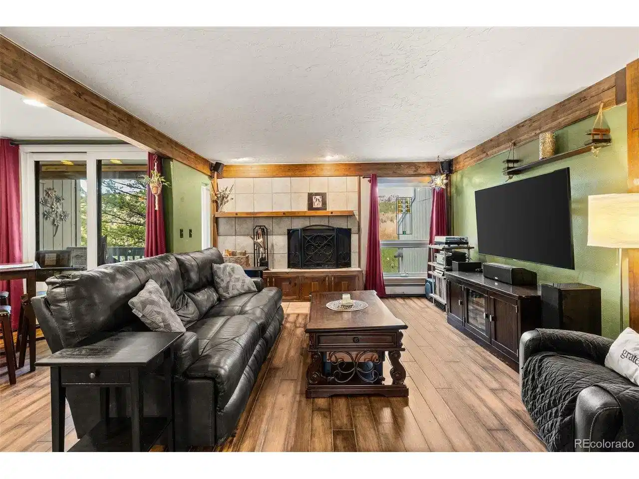 Image 1: Inviting living room with exposed wood beams, a cozy fireplace, and warm mountain character