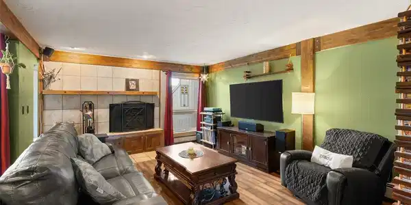 Image 4: Cozy living room with wood-burning fireplace and an open flow into the kitchen and dining area