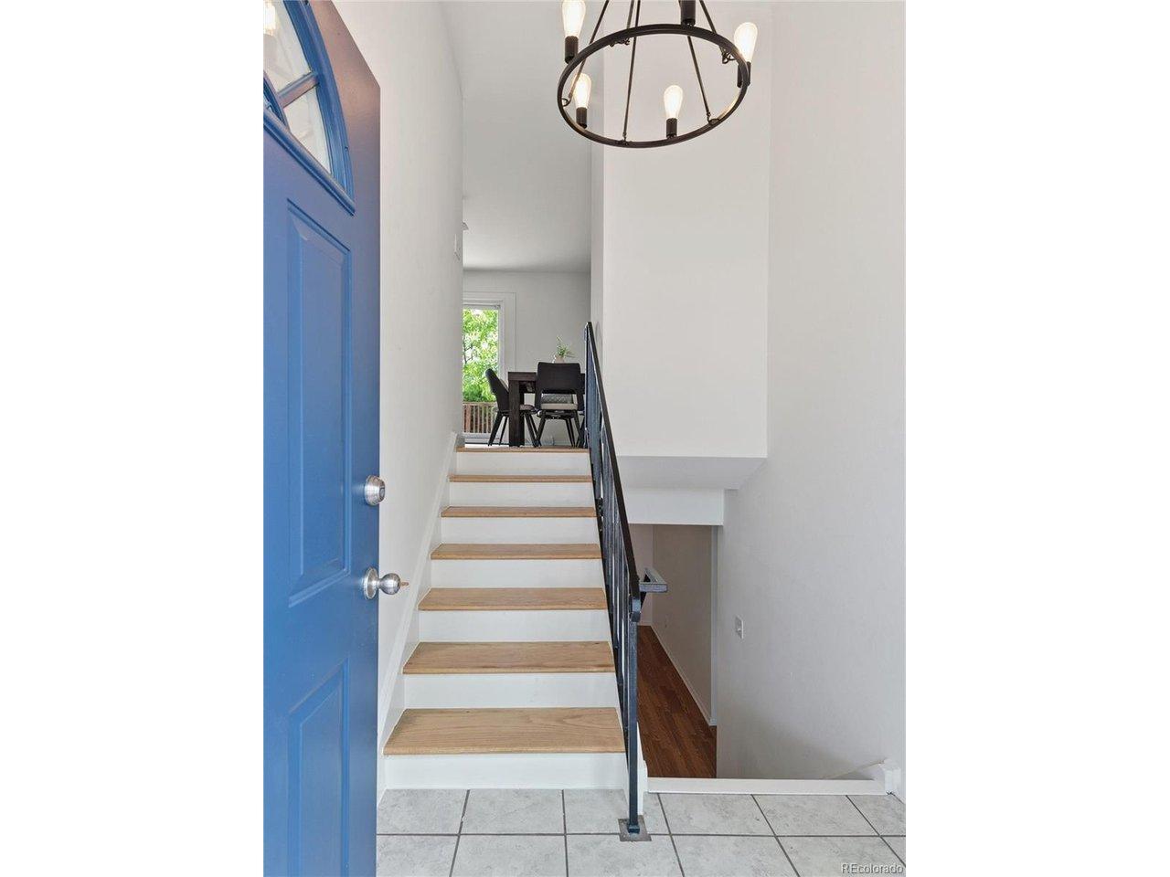 Image 4: A blue front door sets the tone. The entry foyer opens to a staircase leading up to the main living level, with the lower level accessible below. Image 4: A blue front door sets the tone. The entry foyer opens to a staircase leading up to the main living level, with the lower level accessible below.