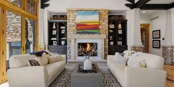 Image 4: The great room features soaring vaulted ceilings with exposed beams, a striking stone fireplace, outdoor access and custom built-in cabinets. Image 4: The great room features soaring vaulted ceilings with exposed beams, a striking stone fireplace, outdoor access and custom built-in cabinets.