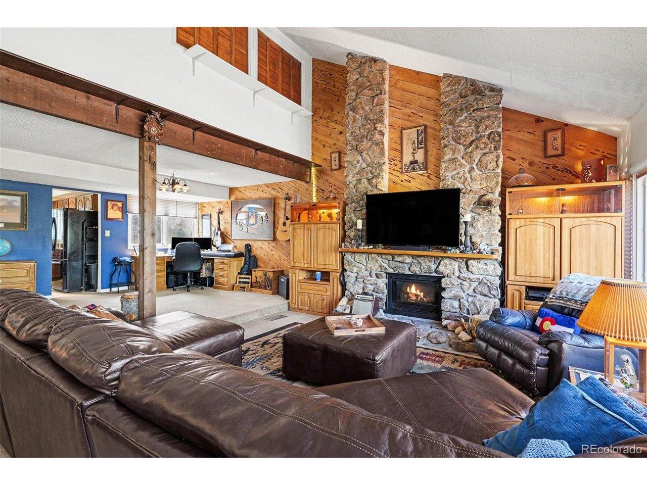 Image 4: Open-concept living and dining spaces connected by a stunning floor-to-ceiling stone fireplace, creating an inviting setting for everyday living and entertaining Image 4: Open-concept living and dining spaces connected by a stunning floor-to-ceiling stone fireplace, creating an inviting setting for everyday living and entertaining