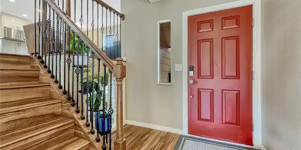 Image 3: The light-filled main foyer introduces the home's stylish bi-level staircase with wrought-iron details, durable wood-look flooring, and upgraded smart home door locks Image 3: The light-filled main foyer introduces the home's stylish bi-level staircase with wrought-iron details, durable wood-look flooring, and upgraded smart home door locks