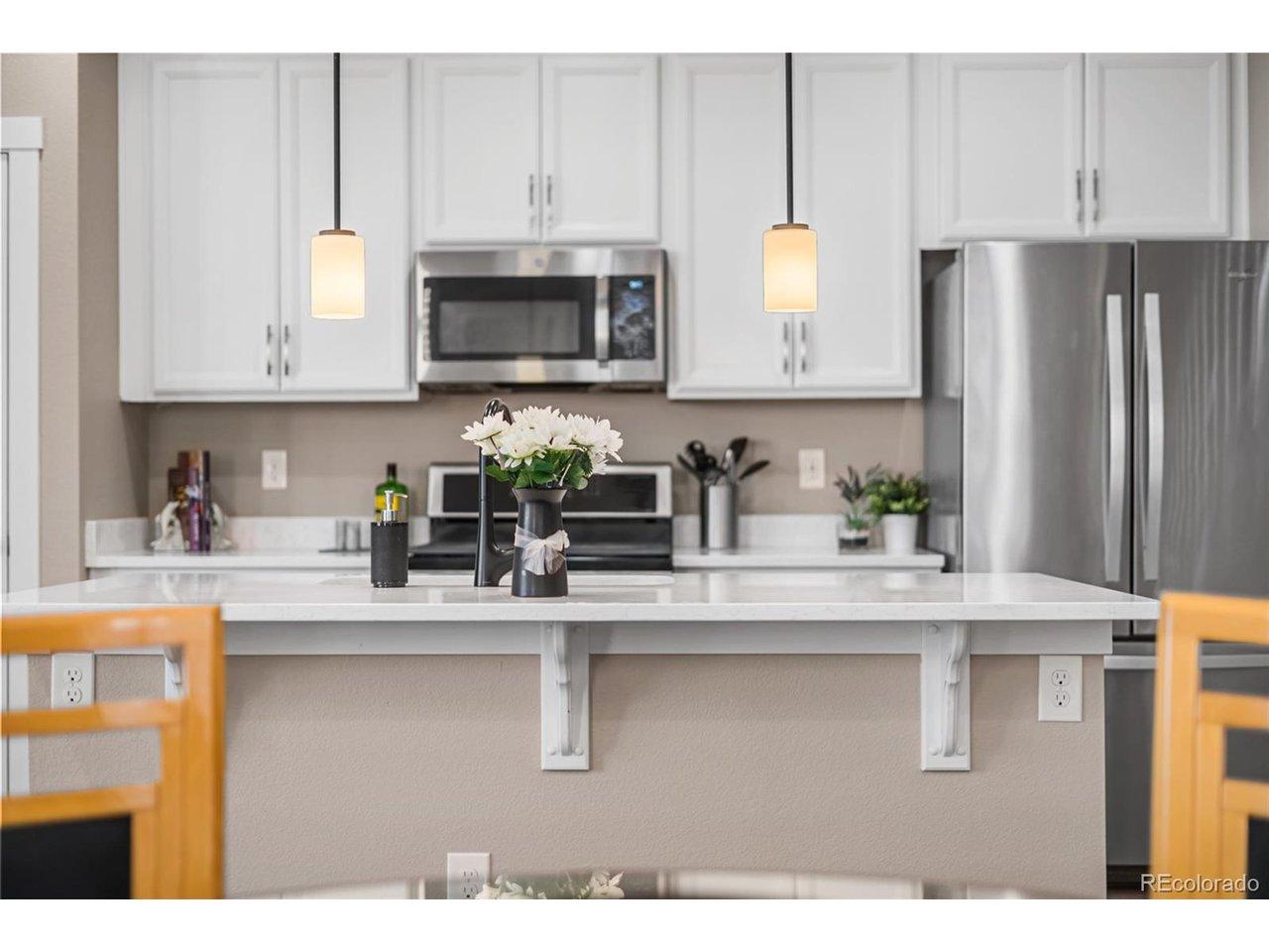 Image 2: Bright, modern kitchen in this Broomfield CO townhouse at 2372 W 164th Pl featuring quartz countertops, pendant lighting, stainless steel appliances, white shaker cabinets, and engineered wood flooring - the heart of this 3 bedroom, 2.5 bathroom attached t Image 2: Bright, modern kitchen in this Broomfield CO townhouse at 2372 W 164th Pl featuring quartz countertops, pendant lighting, stainless steel appliances, white shaker cabinets, and engineered wood flooring - the heart of this 3 bedroom, 2.5 bathroom attached t
