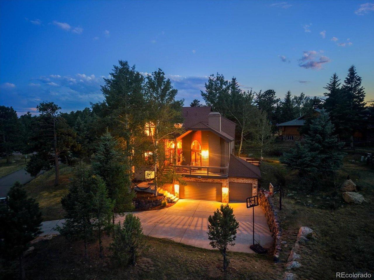 Image 1: Stunning twilight view captures the home's dramatic architecture under a Colorado sunset sky.