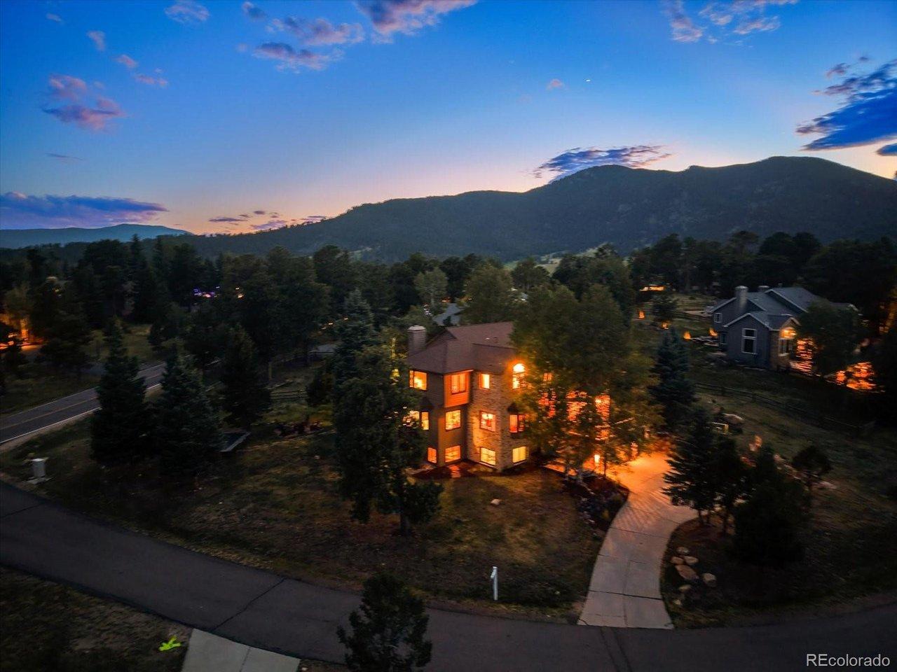 Image 2: Mountain setting with warm interior lighting throughout, showcasing the property's Hiwan Golf Club location and surrounding tree coverage.