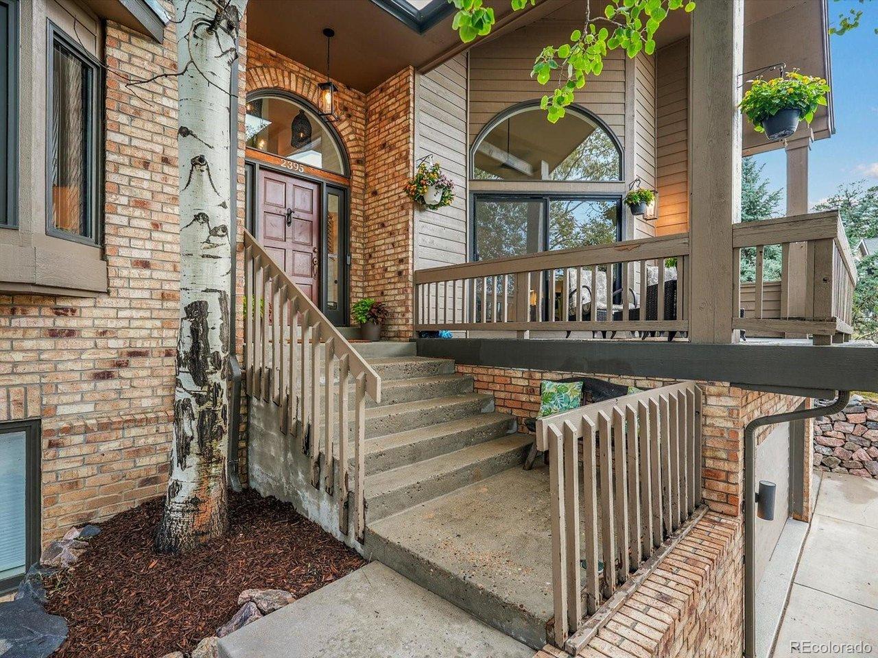 Image 3: Exterior staircase and upper balcony showcase the home's unique multi-level design amid mature aspens.